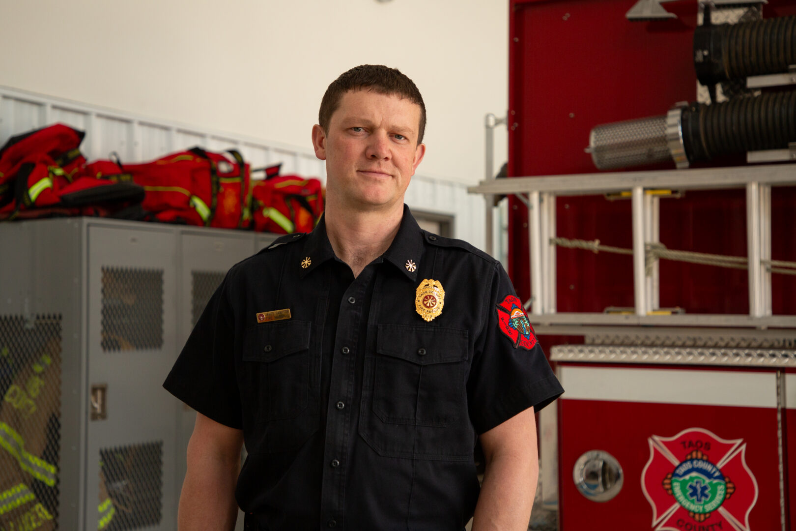 A young fire marshal stands in his uniform in the fire station.